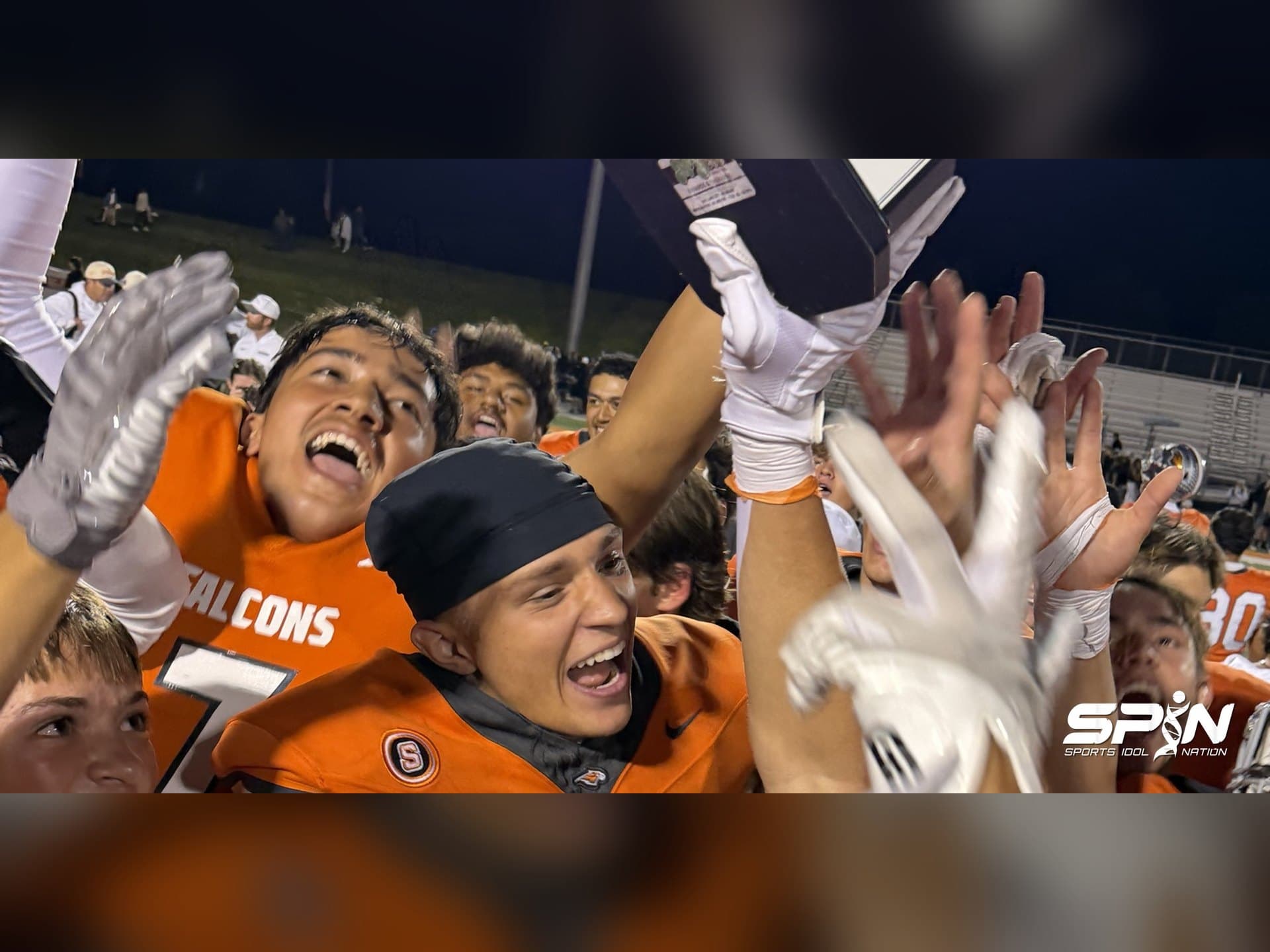 Skyridge players in orange Falcons jerseys hoist a plaque and celebrate after beating Corner Canyon 37-27 in Lehi, Utah, on September 25, 2026.